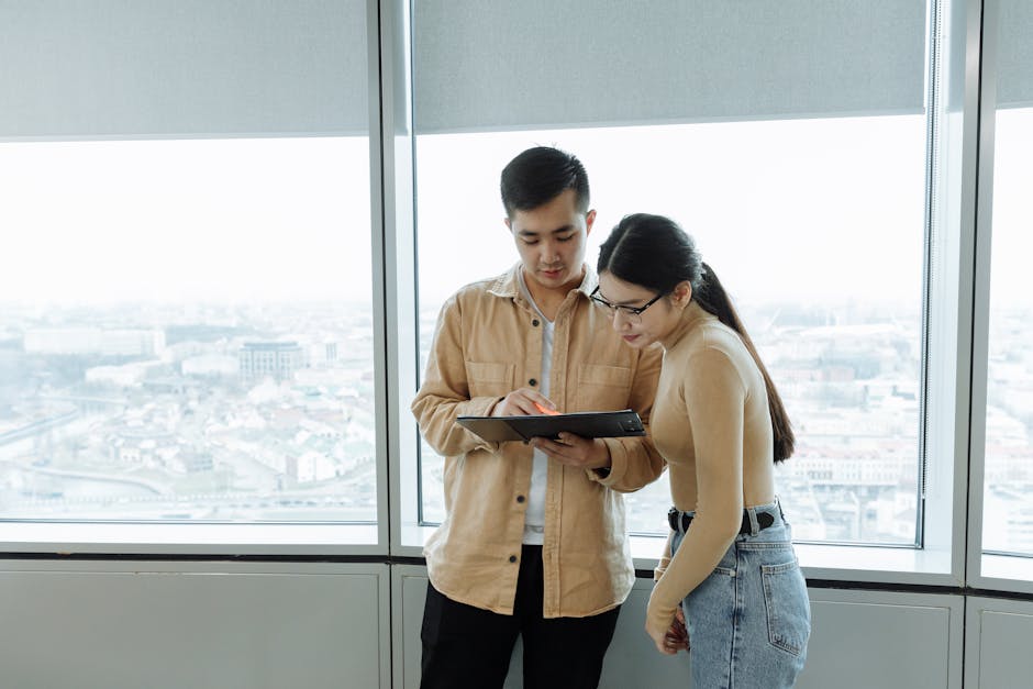Two colleagues working together reviewing documents in a bright office setting.